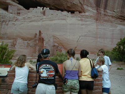 Listening to a a guide.  Anasazi cliff ruins in the background.